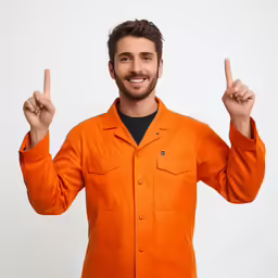 a man in an orange shirt pointing to the camera with a victory gesture