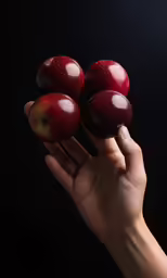 three red apples being held in one hand and two with green apples on top