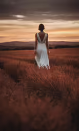 a woman in a white dress is standing by herself and looking out at the grass