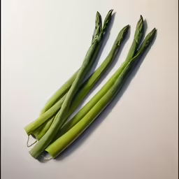 asparagus spears on white background next to a piece of broccoli