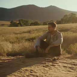 a man kneeling in a field wearing sunglasses
