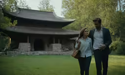 two people walking together in front of an old building