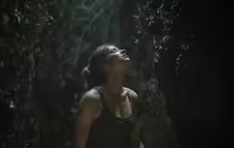 a woman standing next to trees while looking up