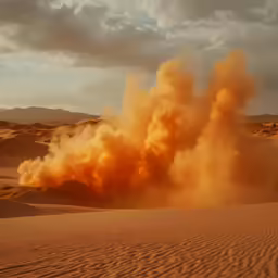 a large explosion of orange smoke in the desert
