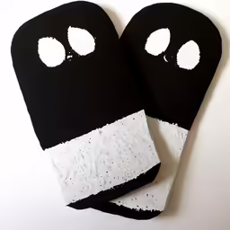 two oven mitts with black and white patches and eyes