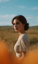 a woman stands in a wheat field under the blue sky