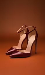 a pair of maroon high heel shoes on top of an orange background