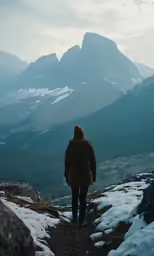 man with backpack walking up the side of a mountain on a snowy trail