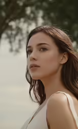 a woman in a white top is staring off into the distance
