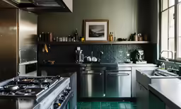 the kitchen has green tile on the walls and a stainless steel stove