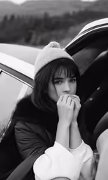 a black and white photo of a woman putting her hands up in the car window