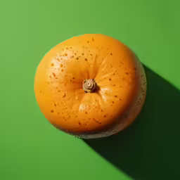 an orange is sitting against a bright green background