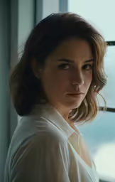 a woman standing near the window with her hand on her head