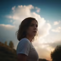 a woman looking out over a field while the sun is setting