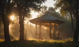 a small, wooden gazebo with fog at sunset in the background