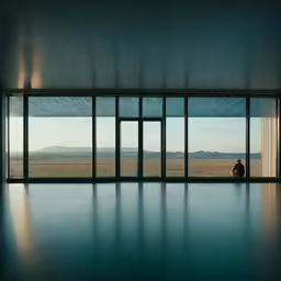 someone sitting in a room looking out to mountains