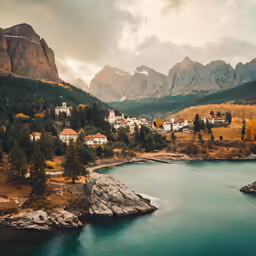 small village on cliff by mountain lake and surrounding area with rock formations