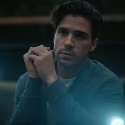 there is a man sitting down with his arms resting his chin on his right hand