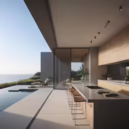an expansive dining room and kitchen outside a modern house overlooking the ocean