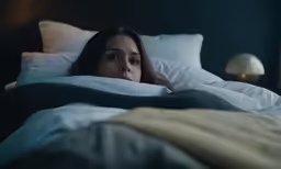 a woman is lying in bed in the dark