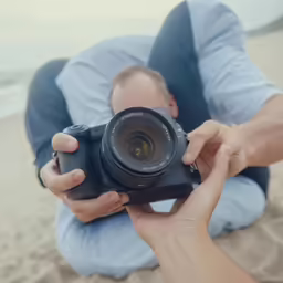 a man holding a camera on a beach