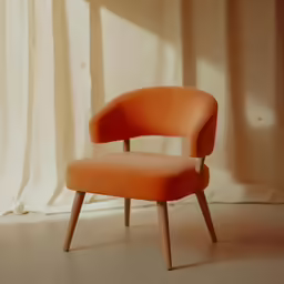 a close up of an orange chair in front of curtain