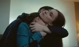 a young woman cuddles an unknown man in the face