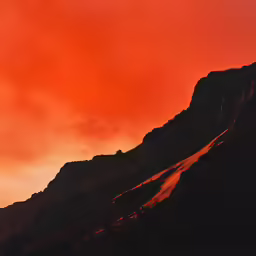 a mountain with red clouds in the background