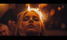 a woman in black top holding yellow fireball and staring down