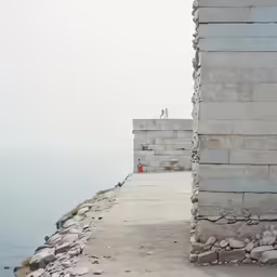 a man standing on the side of a cliff near water