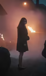 a woman is looking at a fire in the back ground