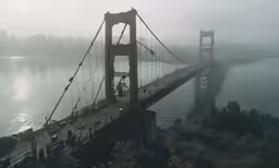 a foggy bay bridge spans over the water