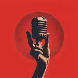 a hand holding a microphone on top of a red background