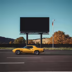 a yellow sports car parked in front of a billboard