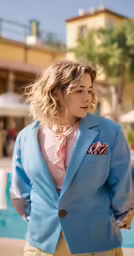 a woman with blonde hair and a blue blazer stands near a swimming pool