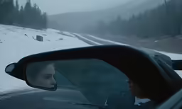 a woman sitting in a car on a snowy road