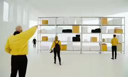 two people standing next to each other in front of stacks of boxes