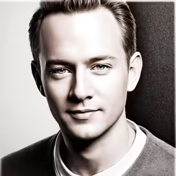 a man in gray shirt with large glasses