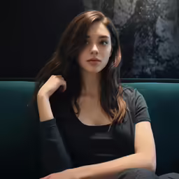 an asian woman wearing dark clothes sitting on a green couch