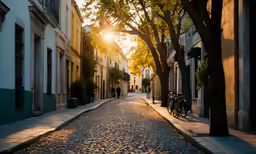 a street with the sun setting on some buildings