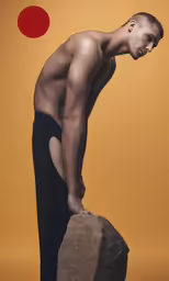 the young man is leaning on the rock
