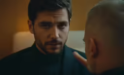 a young man in a suit looking at his reflection in the mirror