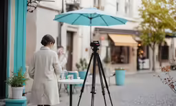 woman in coat using video camera to photograph street corner