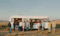 a group of people are standing in front of an old van