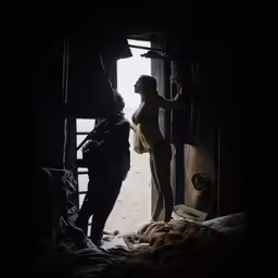 a man and woman in a barn looking out of a door
