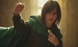 a woman holds up her hair in a green hoodie
