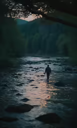 there is a man wading through the water in the sunset