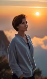 a woman posing on a mountain top at sunset