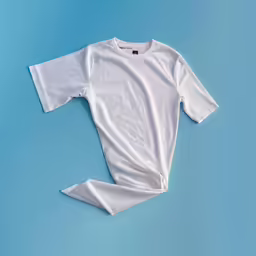 the white tee - shirt is laying on a blue surface