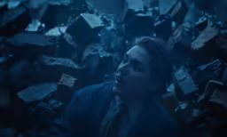 a man in a suit sits inside a room of garbage